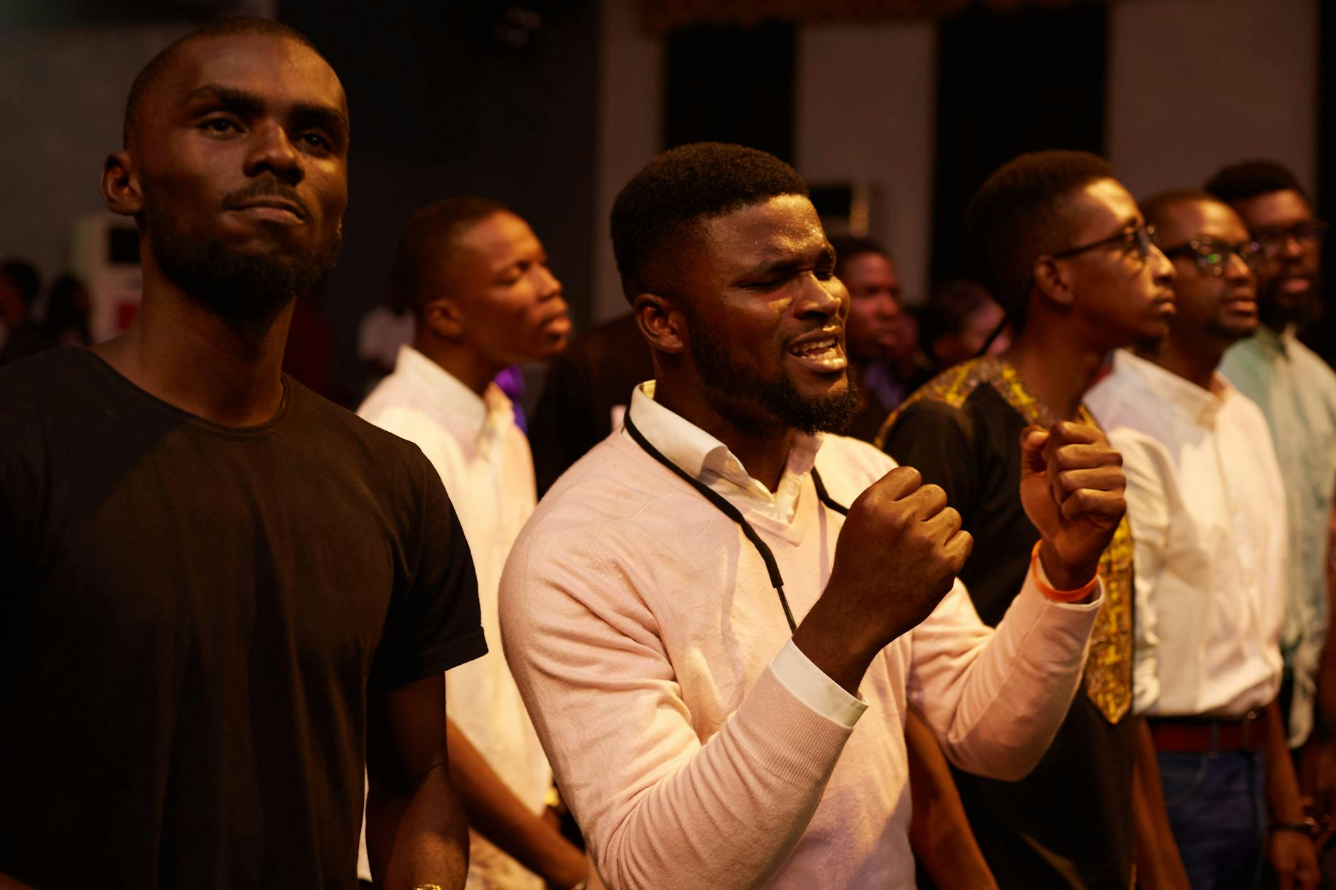 A group of men praying together during an indoor worship service