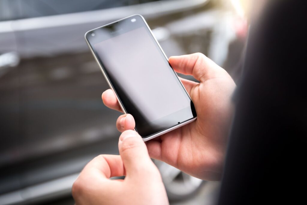 A person holding an Android smartphone with a black, switched-off screen