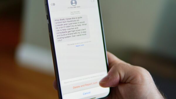 A hand holding a smartphone showing a text message conversation