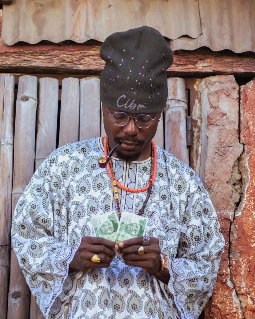 A man in traditional attire and a cap counting money
