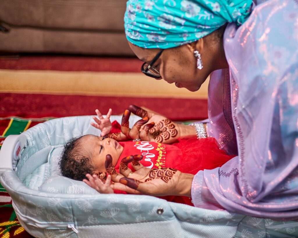 A mother with henna on her hands holding her newborn baby indoors