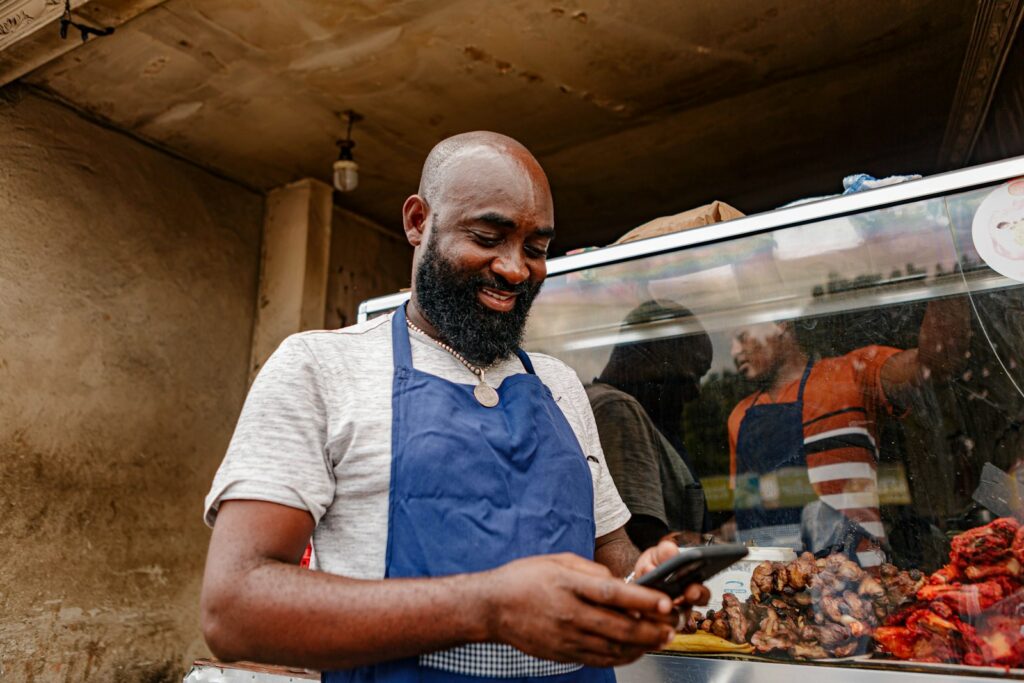 A man in an apron looking at a mobile phone