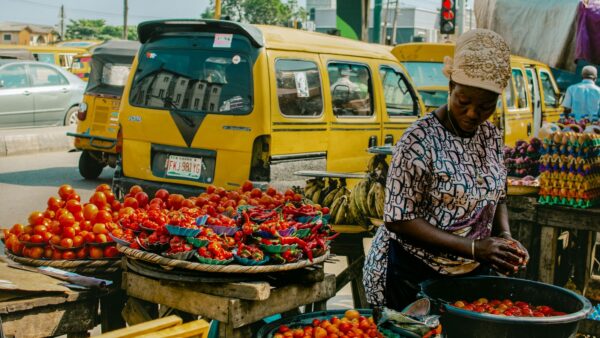A vendor selling fresh vegetables and fruit at a street market stall in Lagos