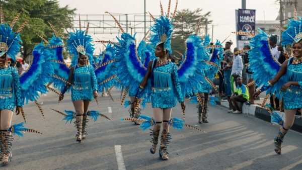 Women in blue carnival costumes walking down a street in Calabar